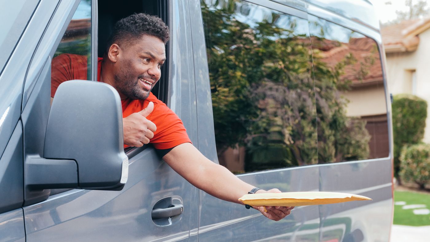 ReadyRoute driver handing a package from the delivery van